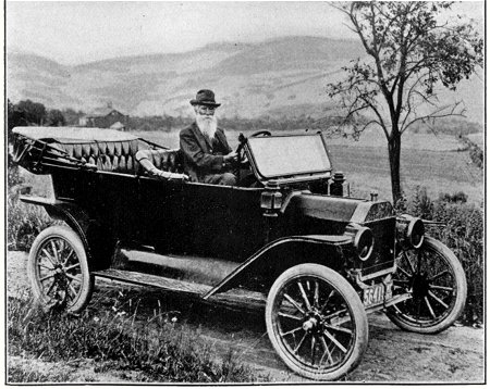 Driving his car on the farm where he drove oxen as a boy